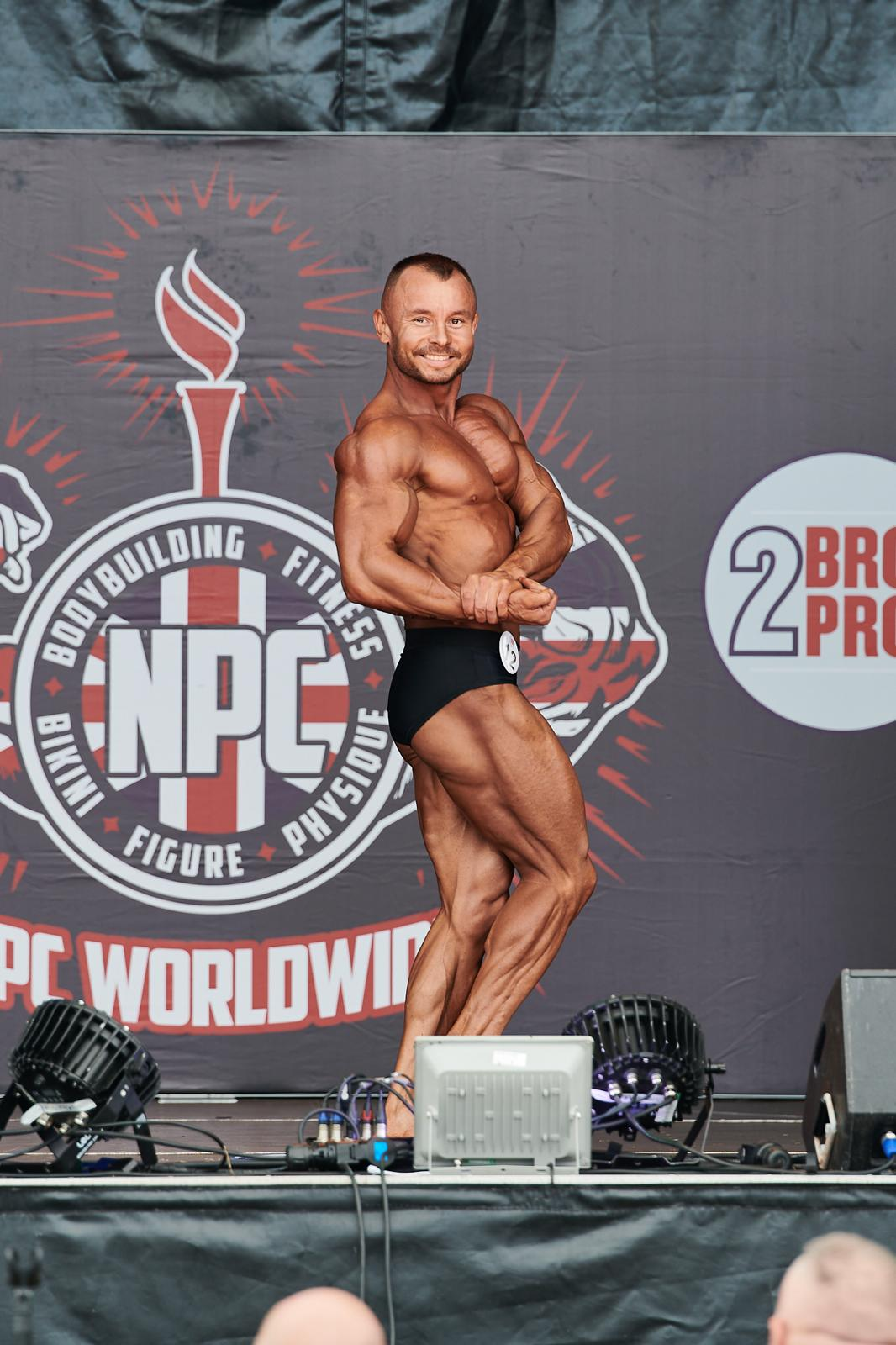 Alin Suciu posing on stage at an NPC bodybuilding competition