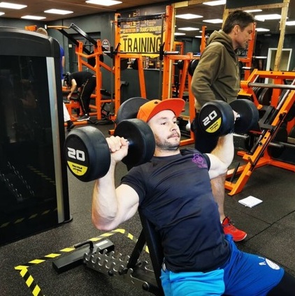 A client pressing dumbbells during a structured gym session