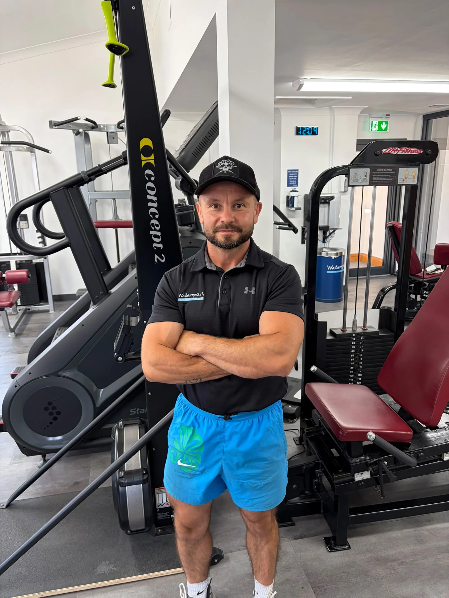 Fitness coach standing beside exercise equipment in the gym