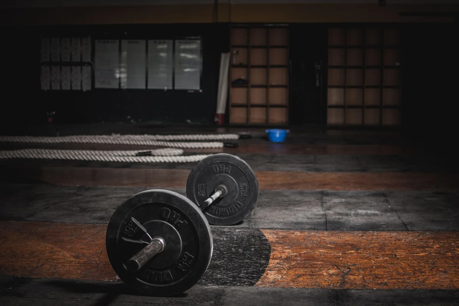 Barbell resting on a worn floor in an empty gym