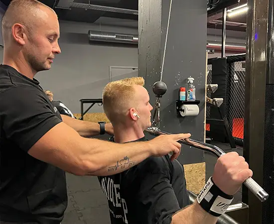 Alin coaching a client on a gym machine